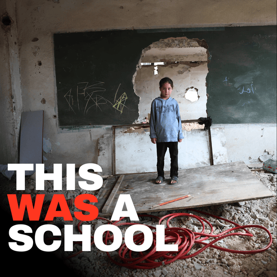 A girl stands in a destroyed classroom